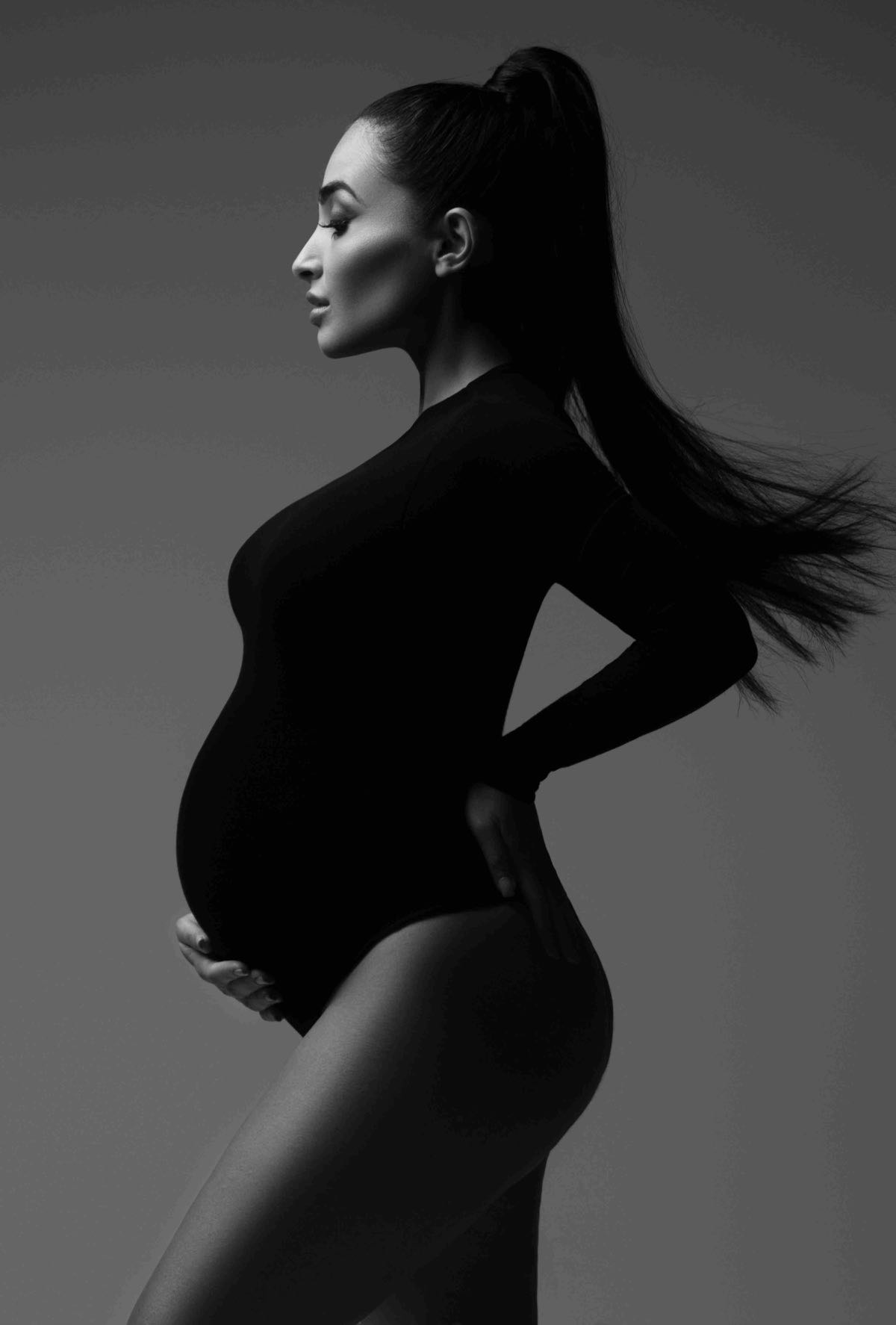 Pregnant woman in a black bodysuit during a fine-art studio maternity portrait