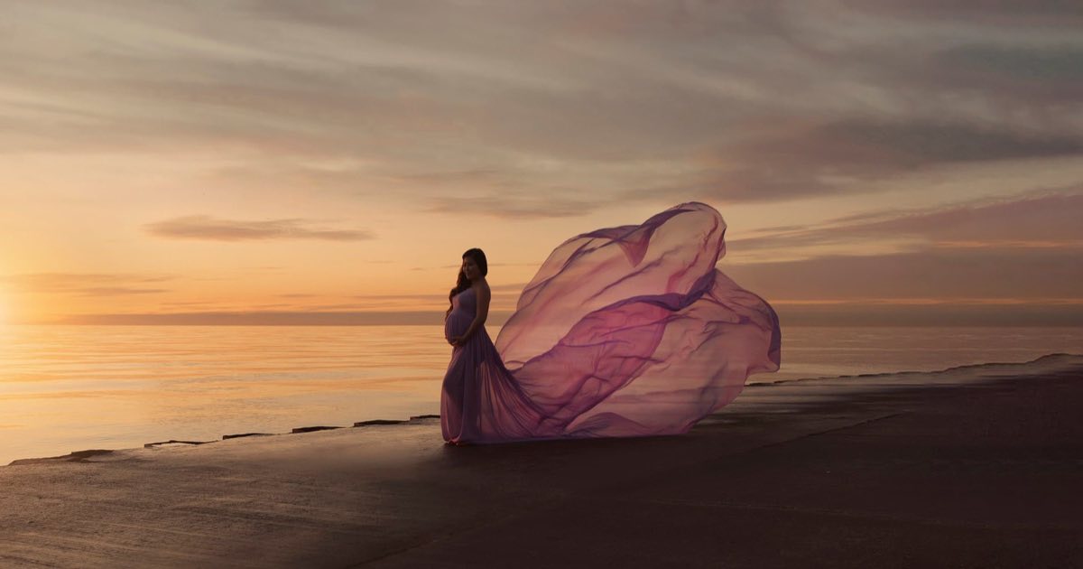 Pregnant woman in a flowing purple gown on Chicago's lakefront at sunset