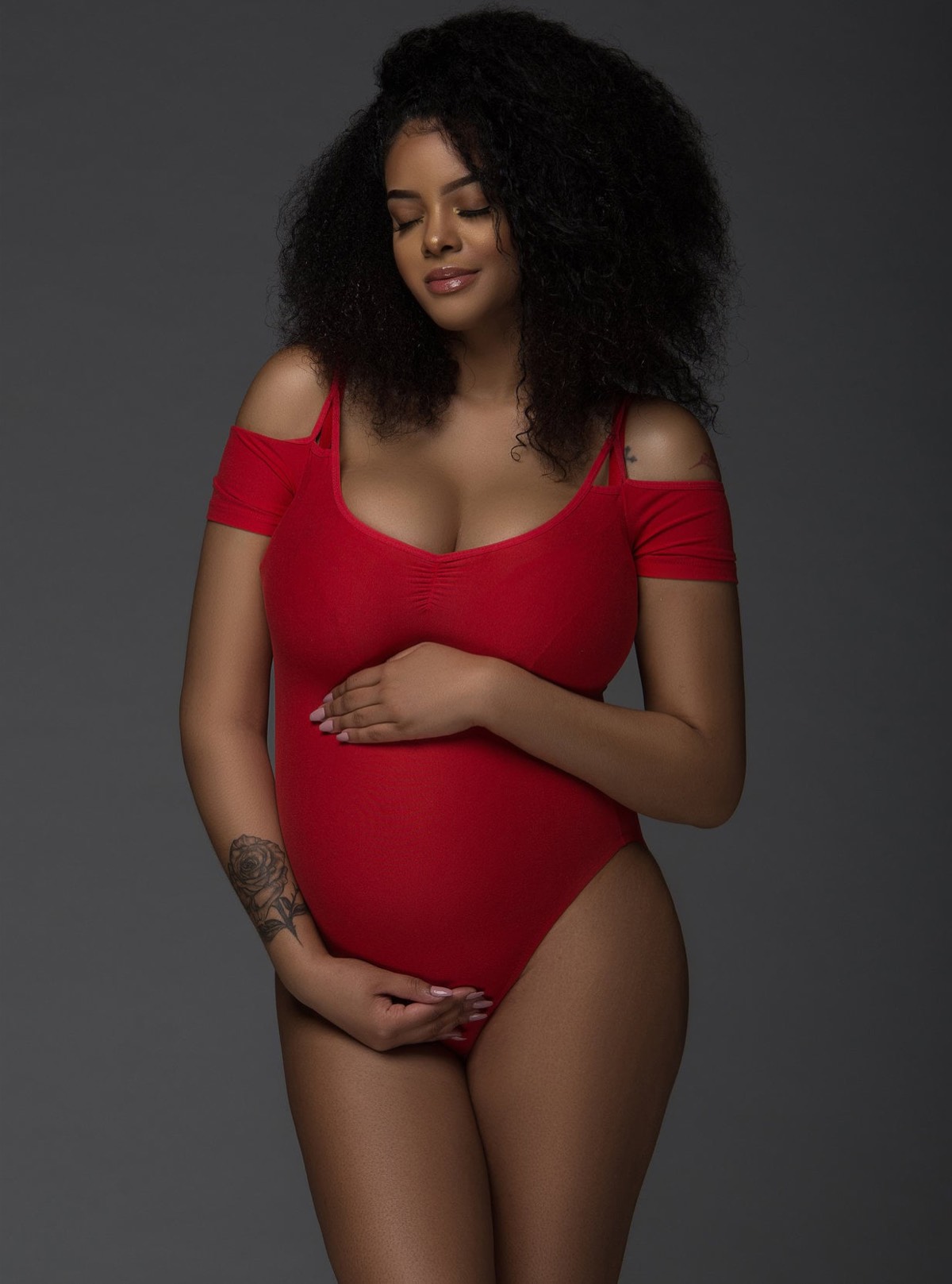 Pregnant mother in a red bodysuit during a Chicago studio maternity photoshoot