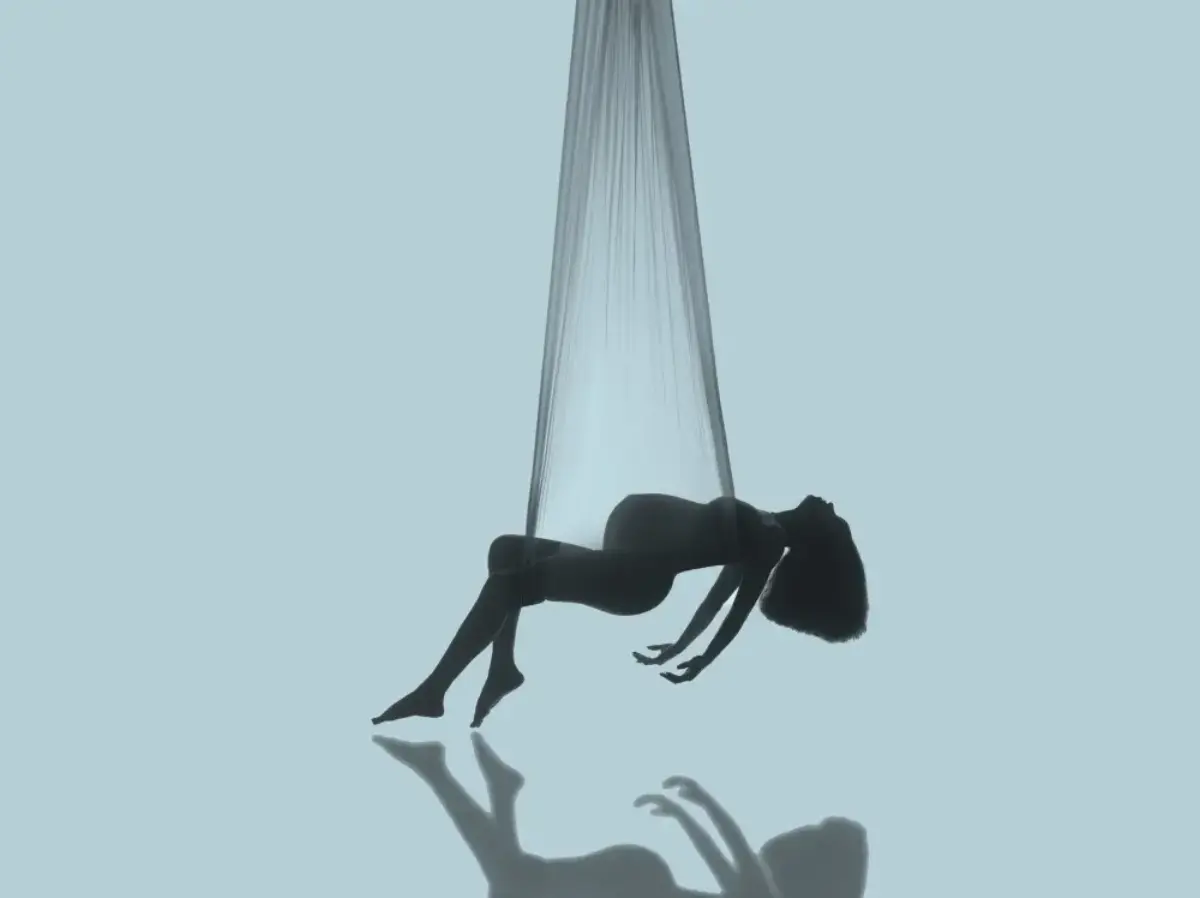 Pregnant woman posing in an aerial-silk maternity portrait with flowing fabric